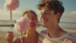 © neatlynatly - A young man and woman enjoy cotton candy together outdoors, with a beach background.