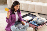 Fototapeta  - Young woman planning vacation with credit card
