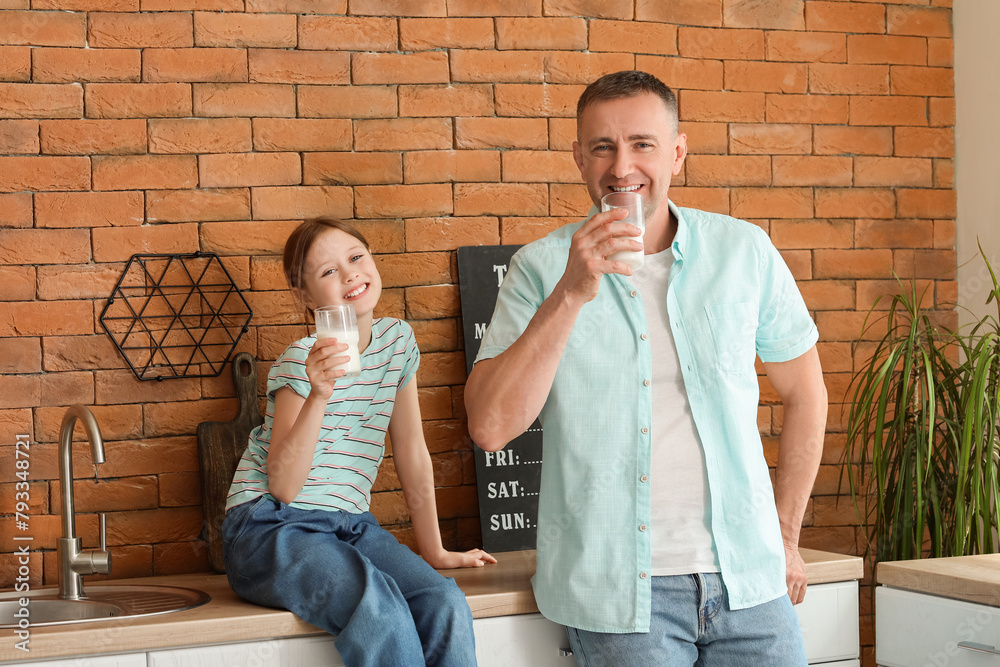 Little girl and her father drinking milk in kitchen