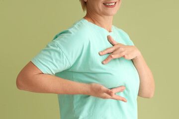 Canvas Print - Mature woman checking her breast on green background, closeup. Cancer awareness concept