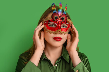 Poster - Beautiful young woman in carnival mask on green background