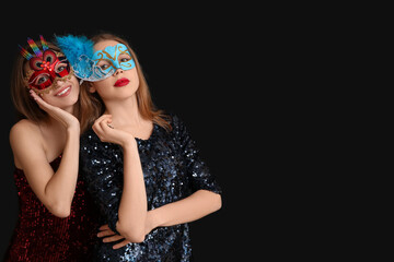 Wall Mural - Beautiful young women in carnival masks on black background