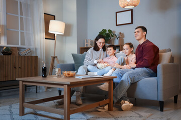 Poster - Happy family with popcorn watching TV on sofa at home in evening