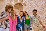 Fototapeta  - A diverse group of tourists, dressed in summer attire, strolls through the tourist city with wide smiles, enjoying their sightseeing adventure