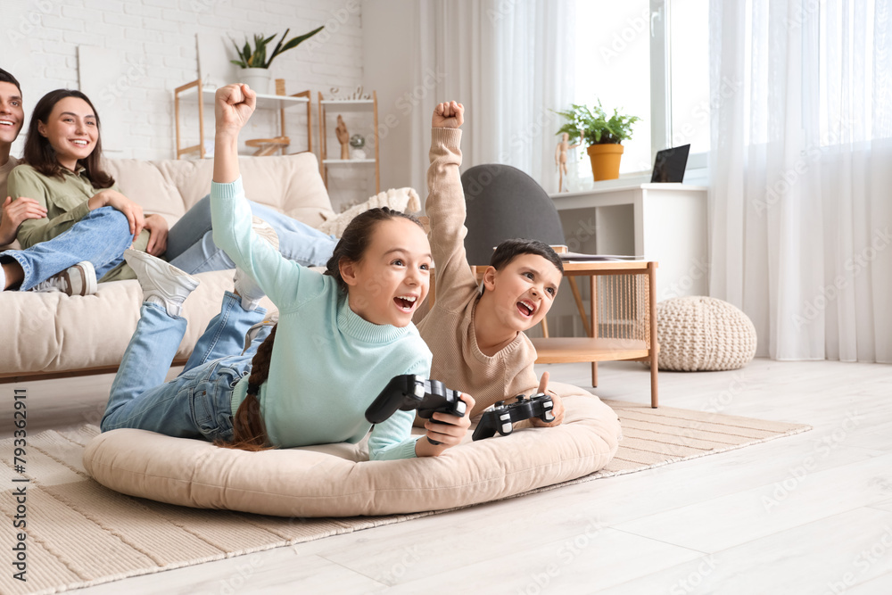 Little children playing video game and his parents at home
