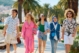 Fototapeta  - A diverse group of tourists, dressed in summer attire, strolls through the tourist city with wide smiles, enjoying their sightseeing adventure
