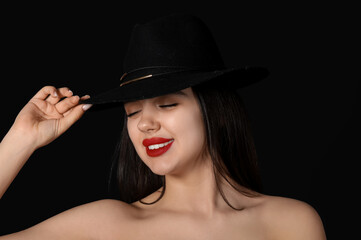 Wall Mural - Happy young woman in hat with red lips on black background