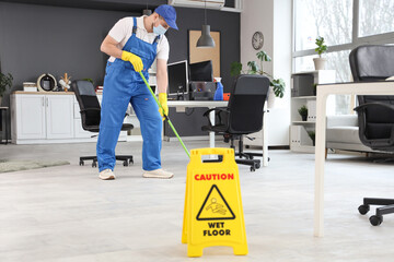 Wall Mural - Male worker of cleaning service mopping floor in office