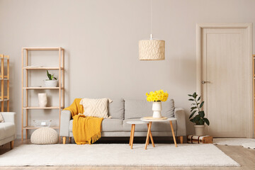 Sticker - Comfortable sofa, shelving unit and coffee table with vase of narcissus flowers in living room