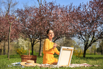 Canvas Print - Beautiful young woman painting in park on spring day