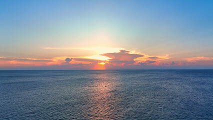 Wall Mural - drone soars over sunset-kissed waves, painting the sky with hues of blue, yellow, and fiery red. nat