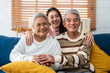 Portrait of Asian senior couple sitting on sofa with daughter in house. 