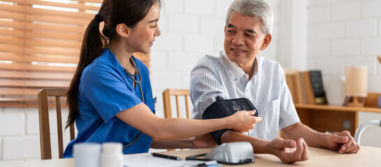 Asian caregiver doctor examine older patient use blood pressure gauge. 