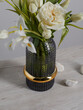 White flowers in a translucent ribbed vase, stones lie against a white wall