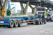 Truck with a trailer and an empty blue long platform rides in the city on the highway under bridge junction