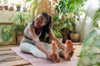 Joyful african american woman stretching, practice yoga. Happy black girl doing pilates workout for good figure. Cheerful female enjoy fitness in urban jungle home garden for flexibility body strength