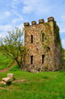 Old castle ruin in sunny spring day & blue sky. Exterior rock brick wall of ancient palace. Castle stone tower and windows with tree in springtime concept. Medieval castle walls palace fort landscape.