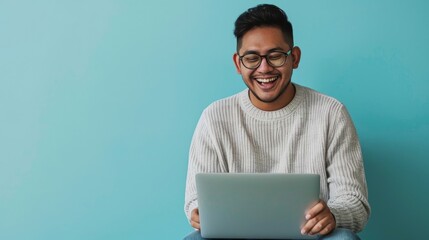 A Latino engineer in a sweater and jeans, laughing lightly while looking at a laptop screen, against a smooth light blue background, styled as a relaxed tech professional.