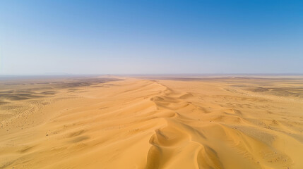 Wall Mural - Aerial view of a vast desert with sand dunes rippling towards the horizon under a clear blue sky