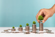 Investment and saving money concept. A man placing coins with growing tree on row of coin money for financial developments and business growth