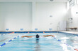 Biracial young female swimmer is training indoors in a pool, copy space