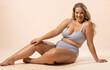 © Wavebreak Media - Caucasian young female plus size model sits on floor in light blue sportswear, copy space