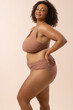 © Wavebreak Media - A biracial plus size model poses on beige background, copy space