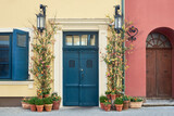 Fototapeta Lawenda - Vintage front door on a old building facade  decorated with flowers and spring flowers in pots.
