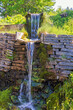 Waterfall by an old mill with a stone wall in the countryside