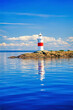 Lighthouse on a skerry with reflections in the water
