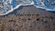 Welcome handwritten on the soft beach sand