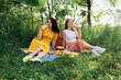 Two friends drink lemonade on a blue blanket for a picnic in nature
