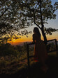 A woman by fence overlooking the city and the sunset