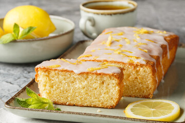 Wall Mural - Glazed lemon pound cake loaf with lemon zest closeup on the plate on the table. Horizontal