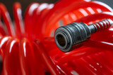 Fototapeta Pomosty - An orange air hose with an hose coupling , closeup. Detail of air compressor hose and pistol
