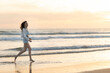 A woman is running on the beach at sunset