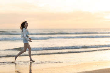 Wall Mural - A woman is running on the beach at sunset