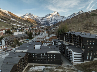 Wall Mural - Town in the alps mountains during sunset. Aerial drone photo. French alps in winter,  Rhone Alpes in France Europe . Les deux alpes village in spring time. Winter French Alpes town  from drone.