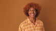 Close up, stylish curly guy laughs while looking at the camera isolated on brown background in the studio