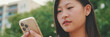© Andrii Nekrasov - Close up, beautiful brunette girl sitting on bench in city park, using phone with mobile app, surfing social media, checking news, Panorama
