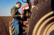 Farmer makes repairs on the tractor in the agricultural field.