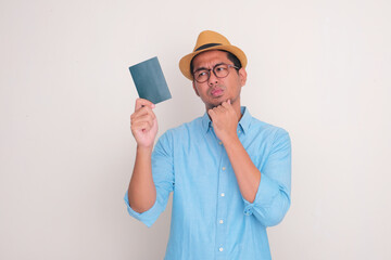 Wall Mural - A man looking to passport that he hold with doubtful expression