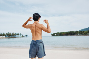 Wall Mural - Muscular Asian Athlete Embracing Fitness and Freedom, Running on Sandy Beach at Sunset