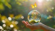 Crystal ball with tree in it in human hand, butterfly flying around it. World Earth day concept, save environment.