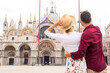 Happy young couple traveling in Venice, Italy - Cheerful tourists visiting venetian landmarks on a sightseeing european tour
