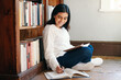 © peopleimages.com - Research, woman and student in library, searching and school with education, studying and knowledge. Person on the floor, college or girl with novel, university or bookshelf with scholarship or notes