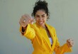 © Savinus - A cheerful and self-assured Latina businesswoman confidently poses in a vibrant yellow suit, extending one arm forward in a dynamic gesture towards the camera.