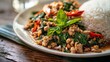 Close-up of a plate of Pad Kra Pao, a savory Thai basil stir-fry with minced meat or tofu, served with rice.