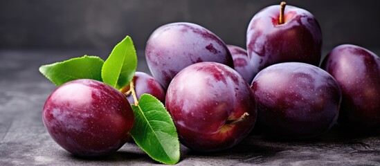 Sticker - A bunch of ripe plums with green leaves on a wooden table