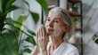 Skincare for mature woman. Portrait of beautiful older woman with gray hair cleaning, taking care of her skin.